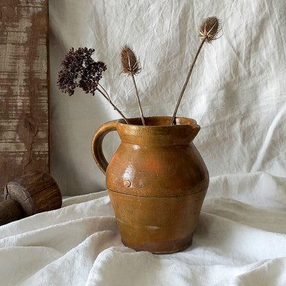 A rustic antique pottery glazed jug, a charming hand-made piece in a lovely shade of ochre with subtle traces of green. Underneath is the French maker's mark.

This piece of stoneware will look wonderful in any interior, particularly those of a rustic, country and farmhouse nature.