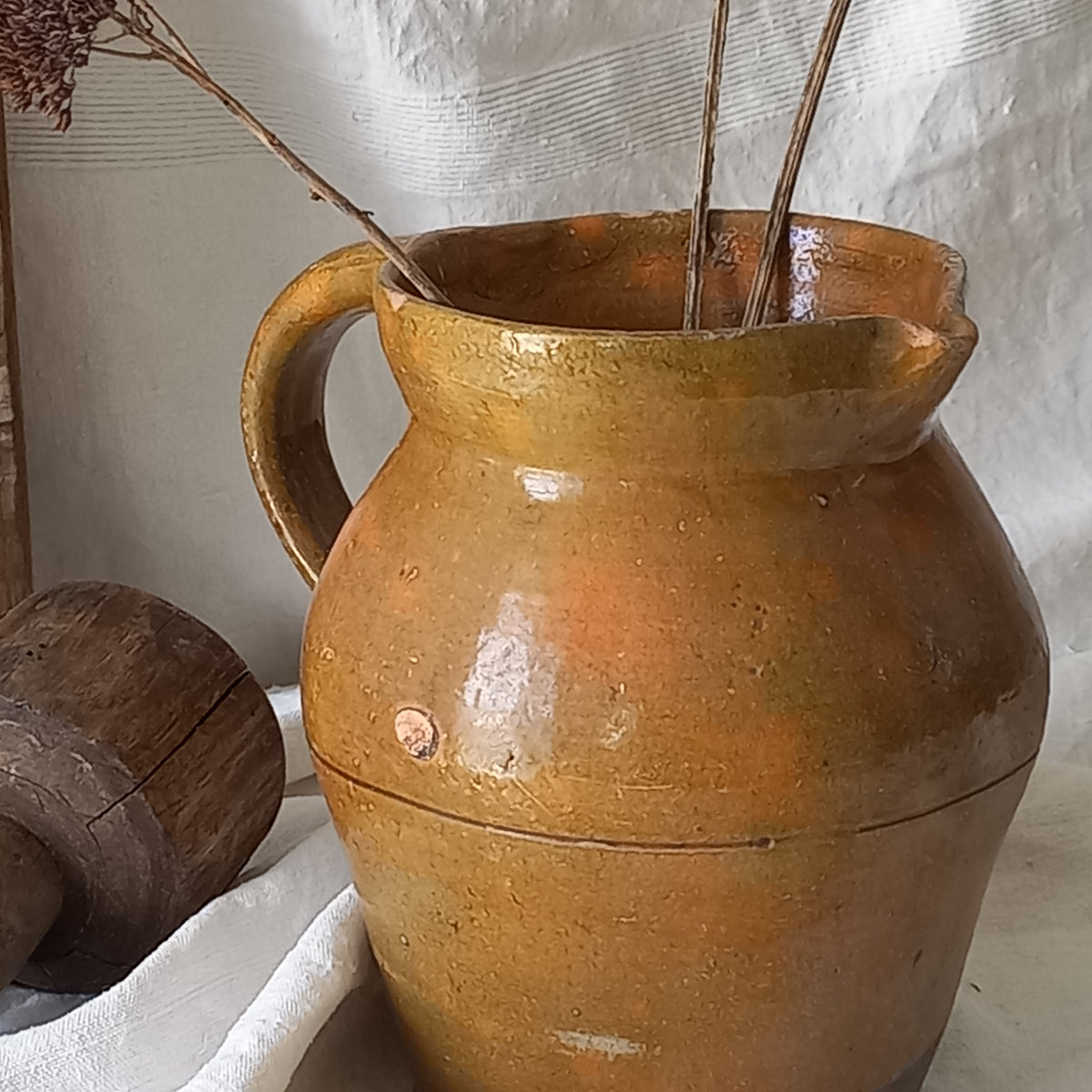 A rustic antique pottery glazed jug, a charming hand-made piece in a lovely shade of ochre with subtle traces of green. Underneath is the French maker's mark.

This piece of stoneware will look wonderful in any interior, particularly those of a rustic, country and farmhouse nature.
