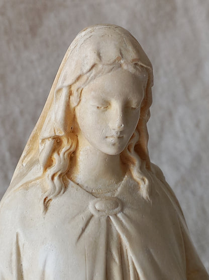 Carved stone sculpture of a draped figure with detailed facial features on a neutral background