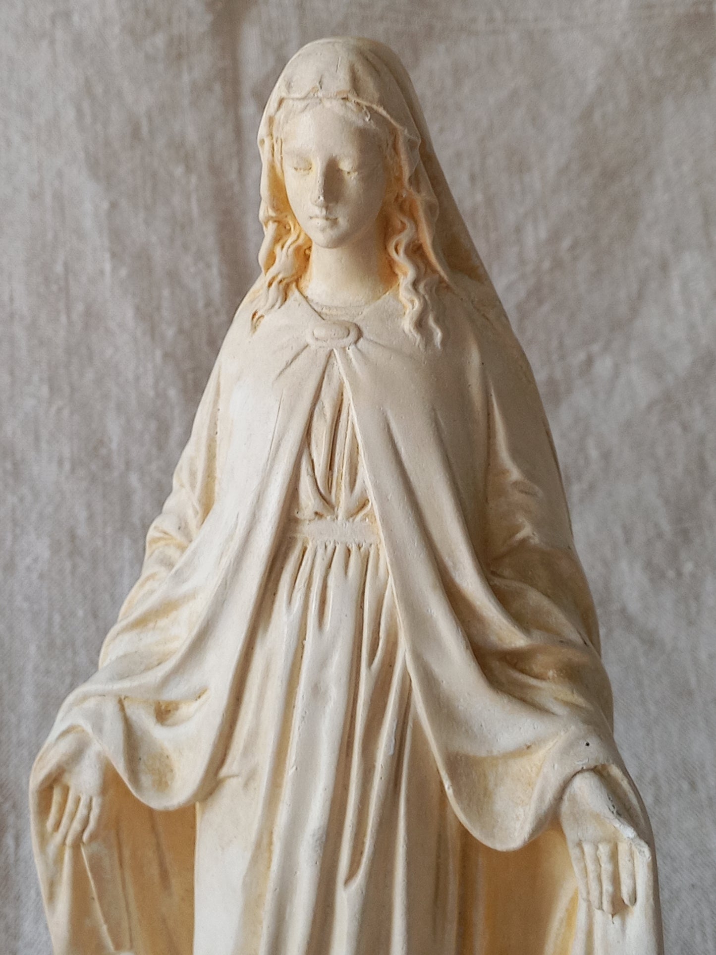 Statue of a draped figure on a textured beige background