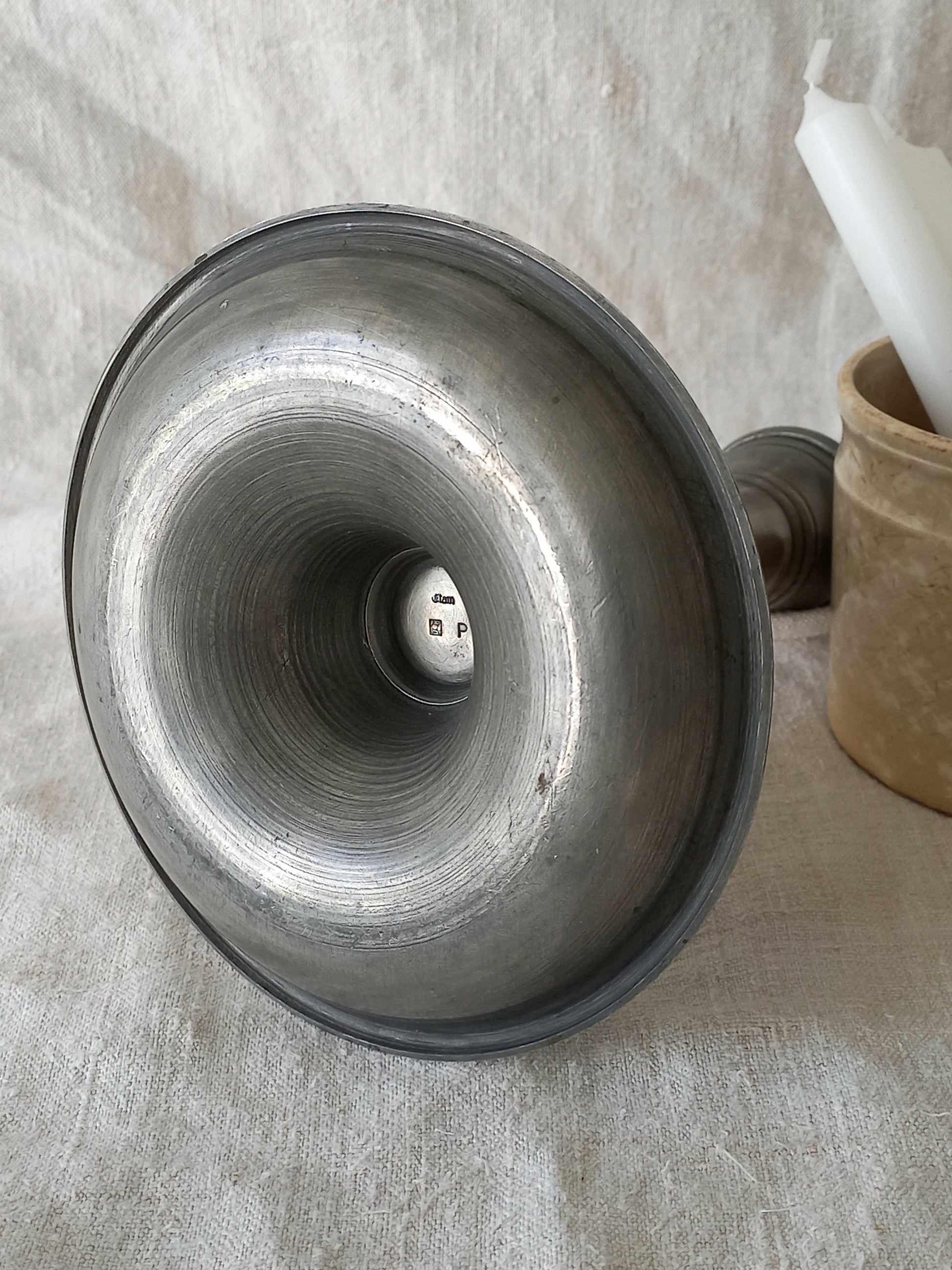 pewter candlestick holder on a textured white fabric background