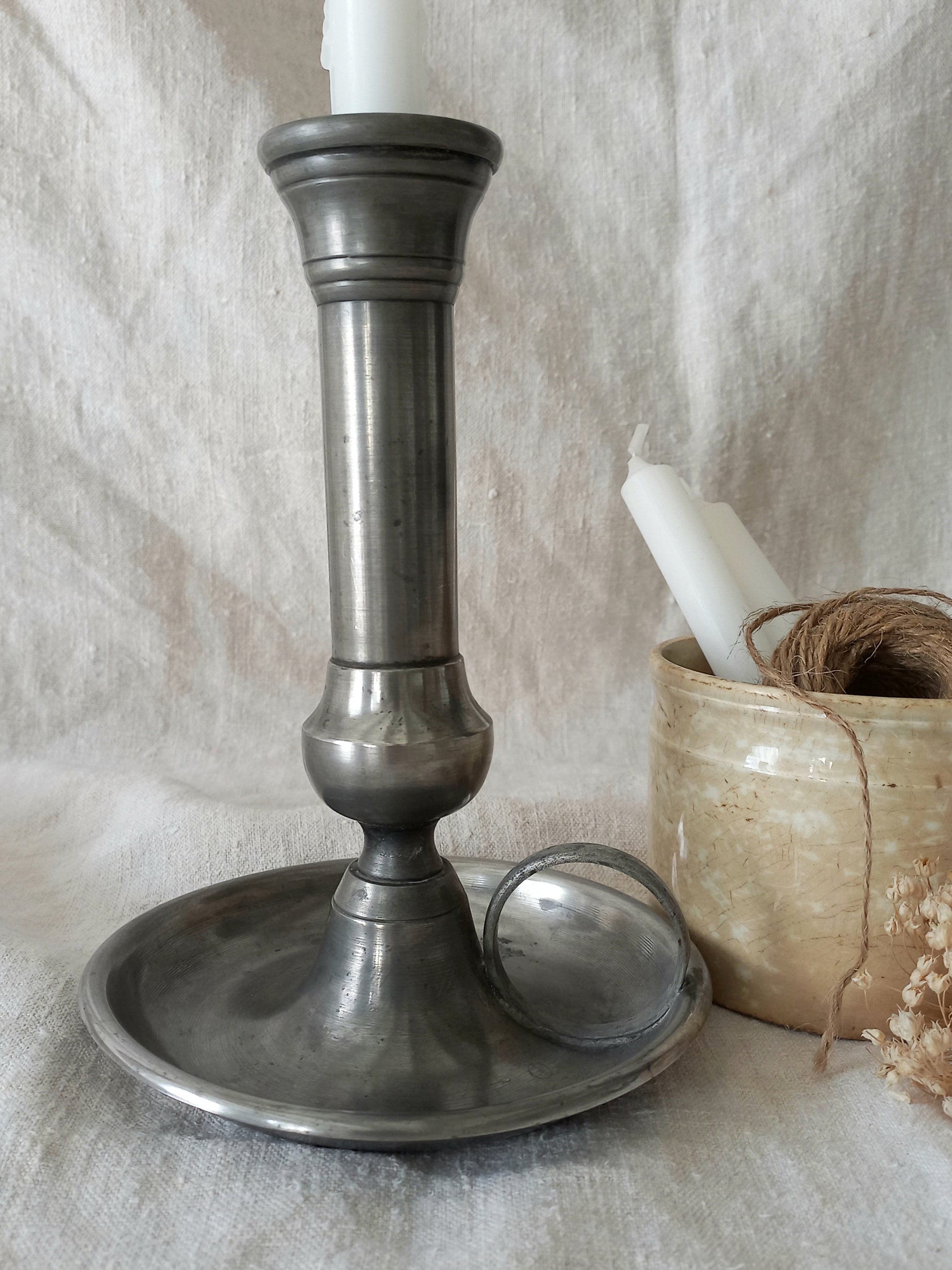 Metal candle holder with a white candle on a textured surface