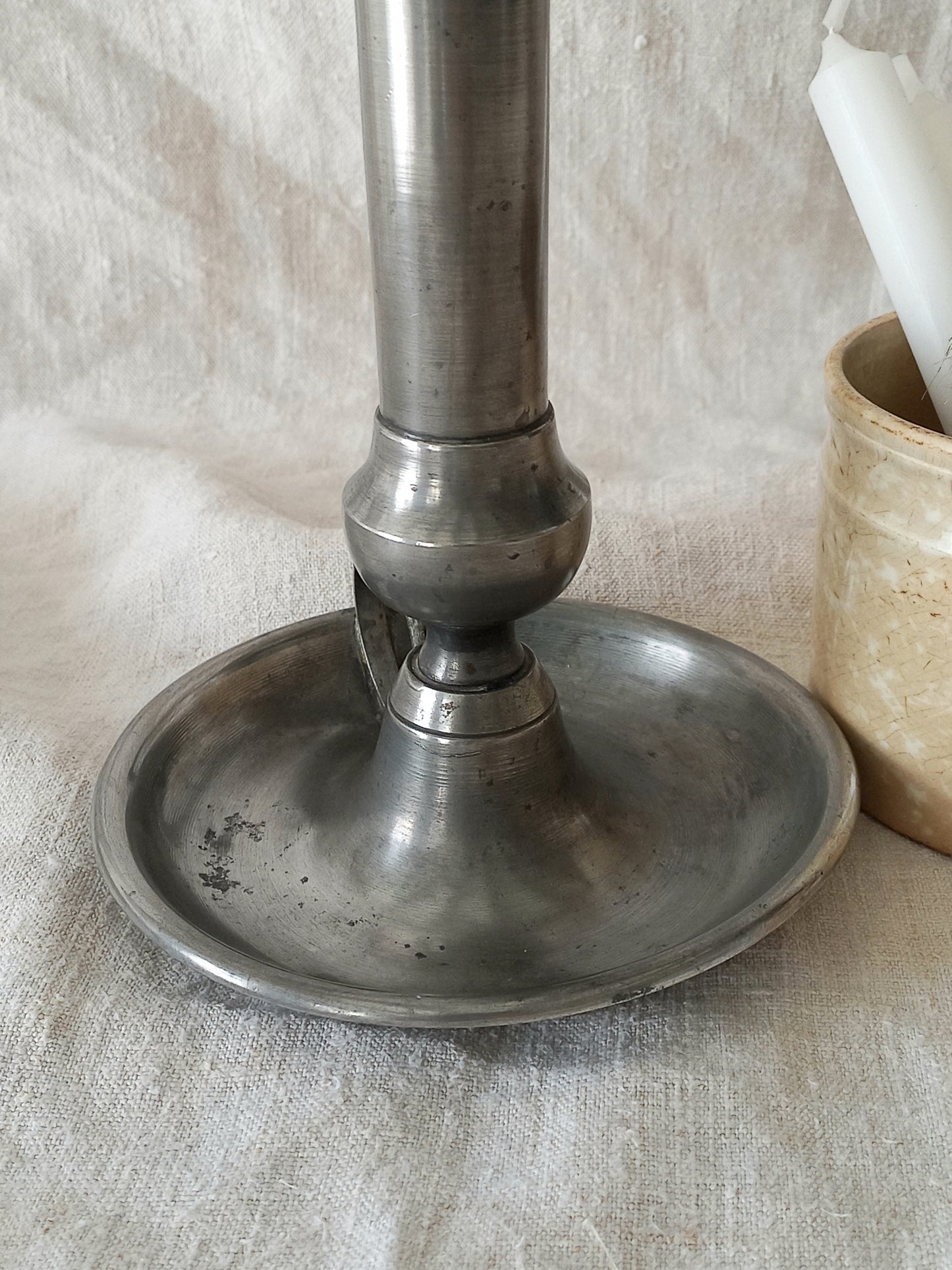 pewter candlestick holder on a textured white fabric background
