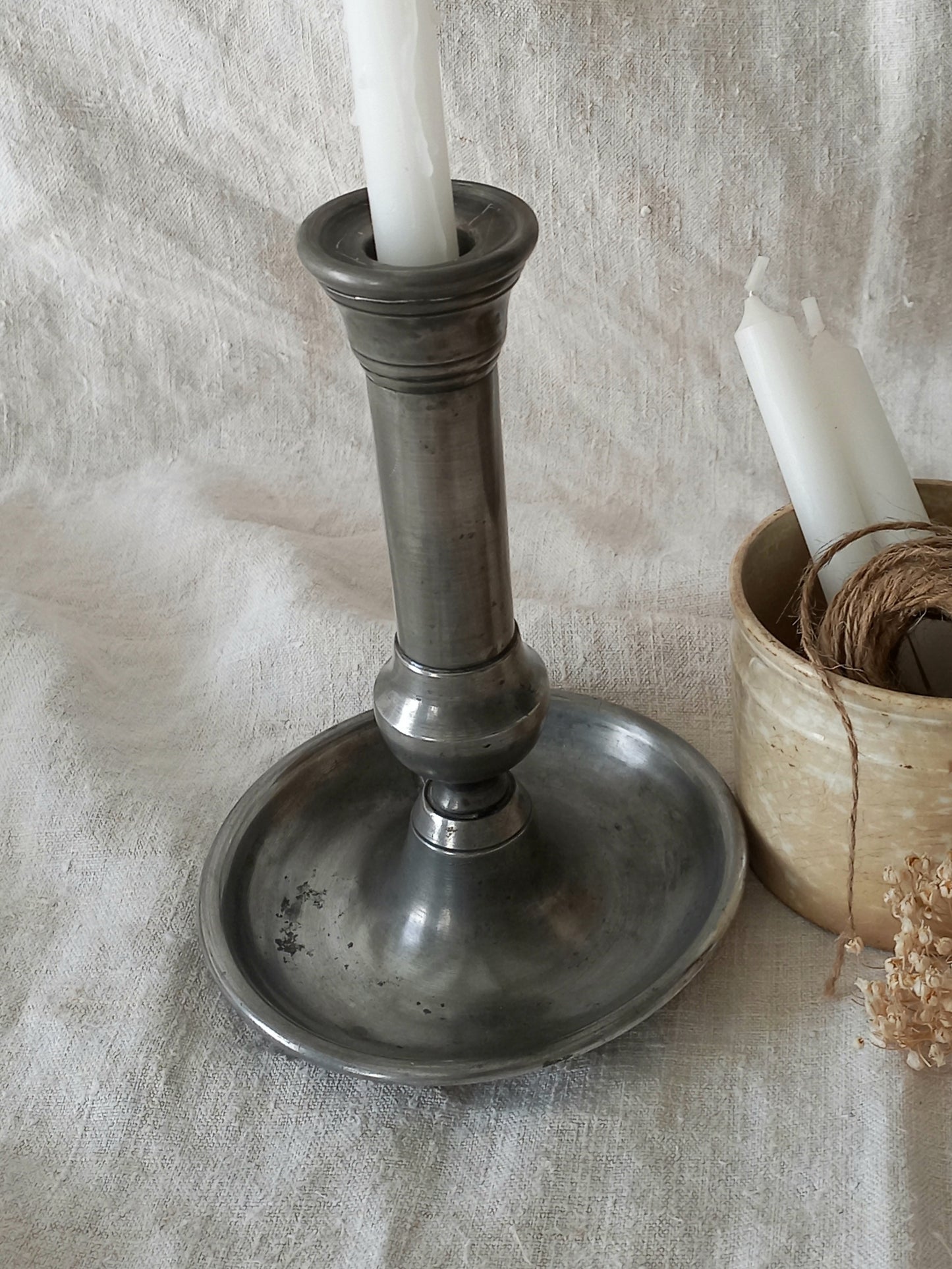 pewter candlestick holder on a textured white fabric background