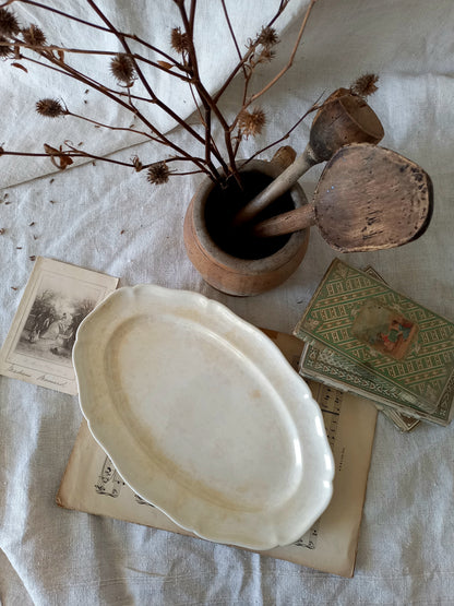 A beautiful vintage oval ironstone serving plate with decorative edges in a time-worn creamy white with super tea-staining that gives it that shabby chic finish many of us desire.